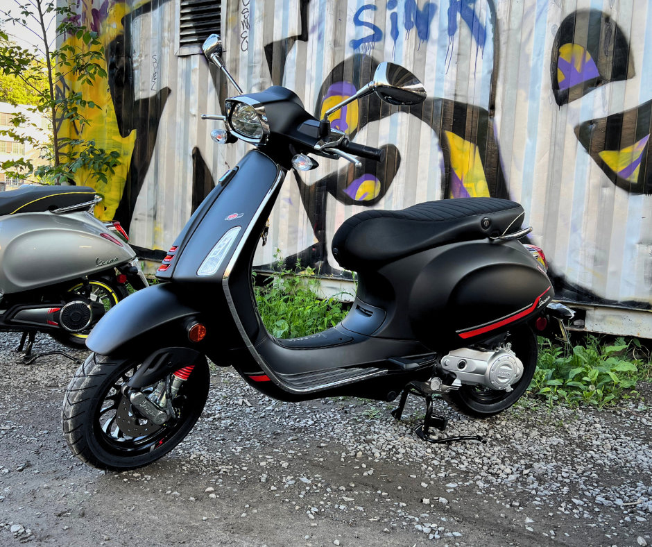 side view of a Vespa scooter in front of a graffiti covered wall