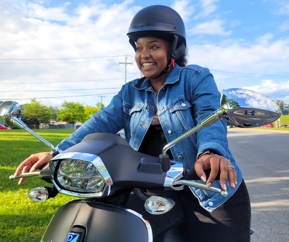 view of a young woman wearing a security helmet riding a Vespa