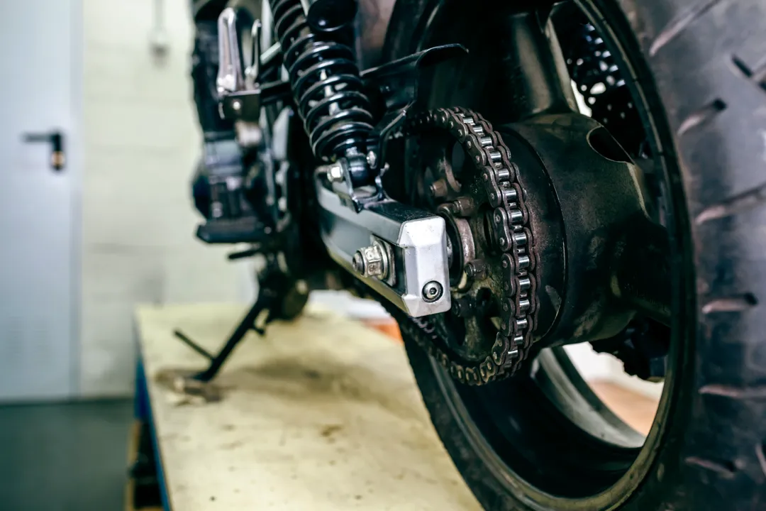 Détail de la roue d'une moto avec les chaînes bien ajustées.