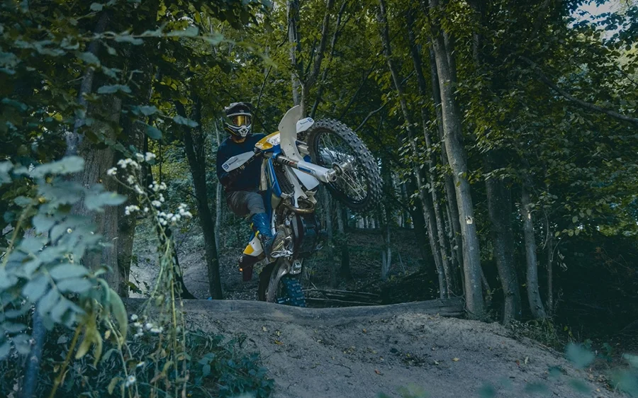 Motorcyclist riding a Husqvarna motorcycle in the forest.