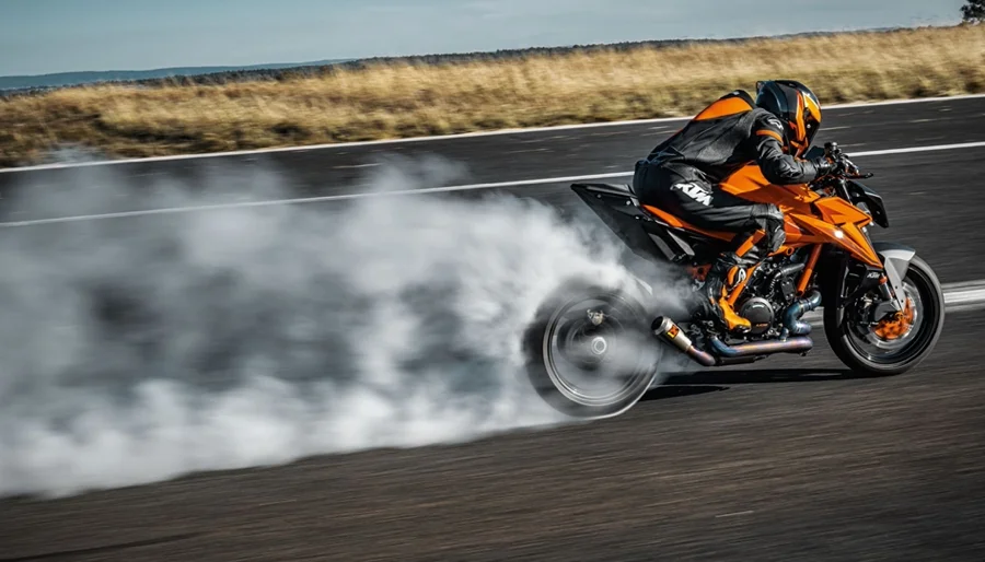 Side view of a motorcyclist riding a KTM motorcycle on a road.